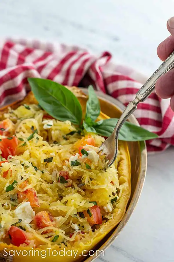 Spaghetti Squash with tomatoes, basil and feta cheese baked in on a marble counter.