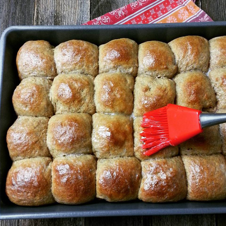 sprouted wheat dinner rolls in a pan with melted butter brushed on top