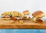Meatball sandwiches on a cutting board over a blue cloth.