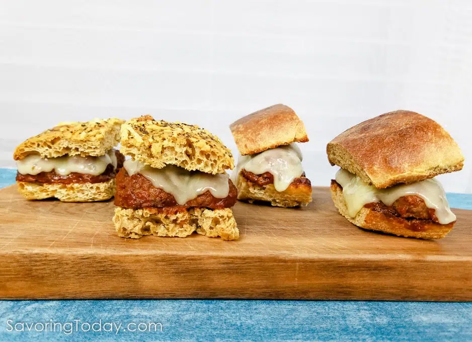 Meatball sandwiches on a cutting board over a blue cloth.