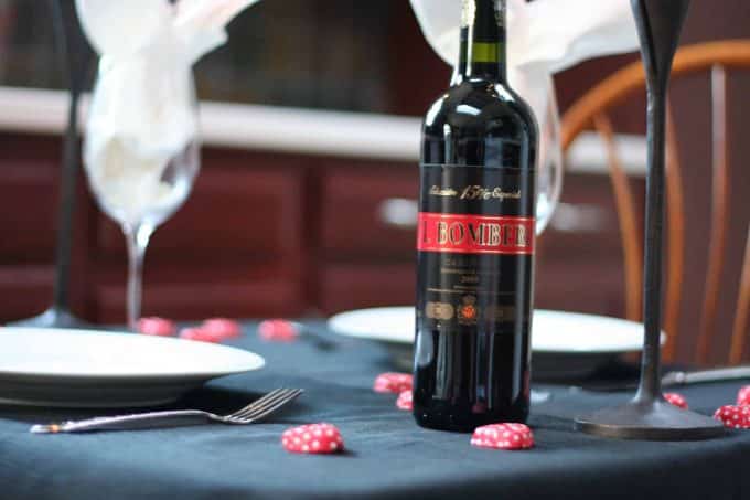 Chefs Table set up in a kitchen for dinner for two with a wine bottle and candies.