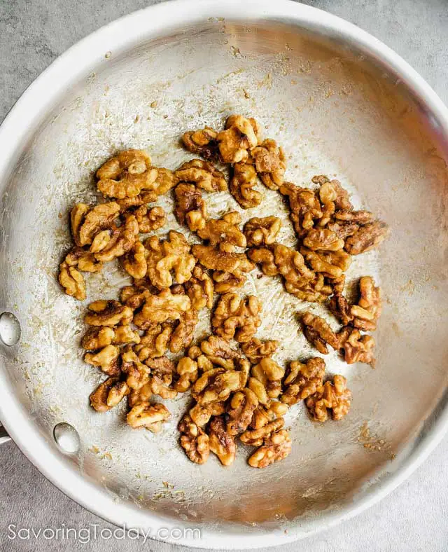 Maple candied walnuts in a stainless steel skillet.