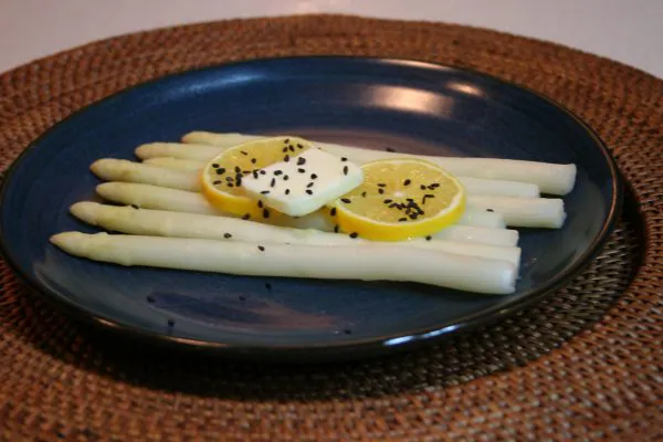 White asparagus on a blue plate with lemon and butter.