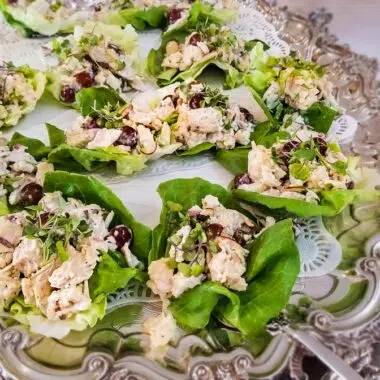 Curry chicken salad on butter lettuce leaves on a silver tray.