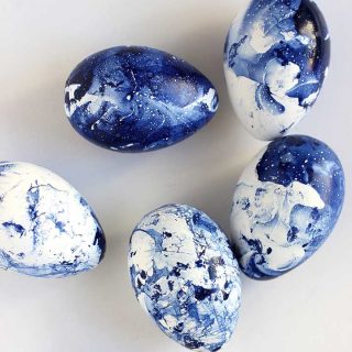 Blue marbled eggs dyed with nail polish on a white background.