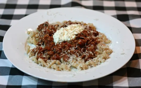 Spaghetti Bolognese served over gluten free pasta or and garnished with ricotta.