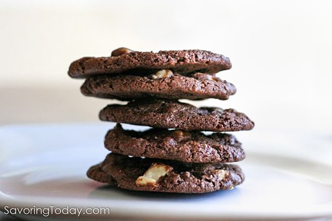 Triple chocolate cookies stacked on a white plate.
