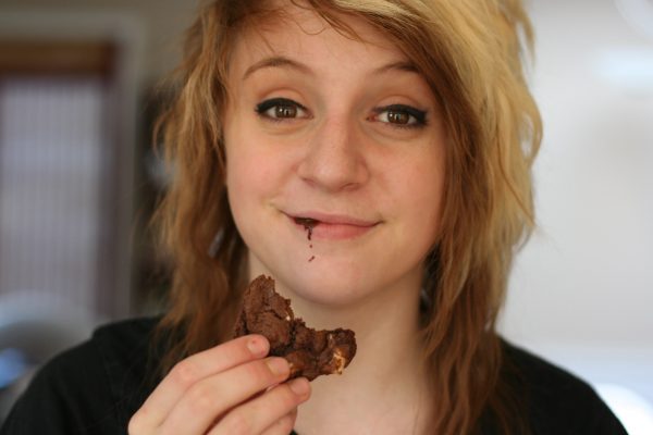 Girl eating a chocolate cookies with melted chocolate on her chin.