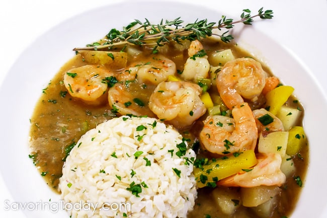Close-up of shrimp stew with rice garnished with fresh thyme in a white bowl.