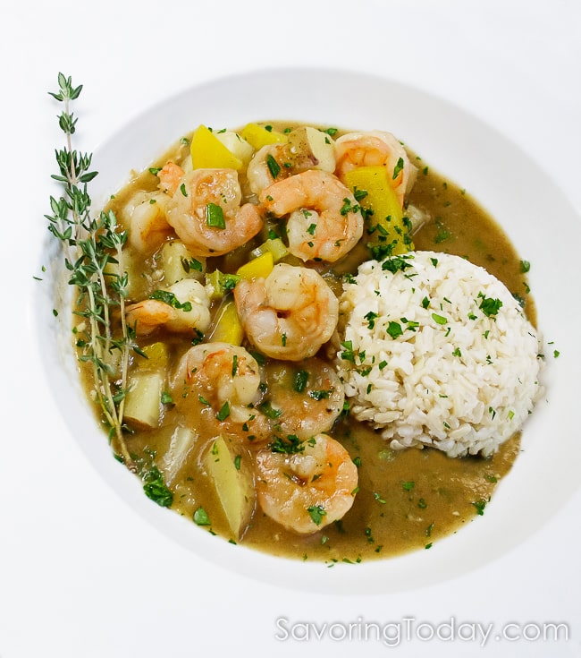 Shrimp stew with brown rice garnished with fresh thyme twigs in a white bowl. 