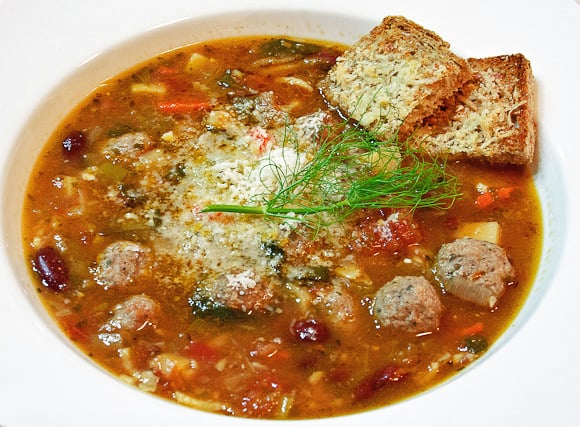 Soup with meatballs in a white bowl.