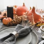 beautiful table setting with grey places and napkins and pumpkin centerpieces