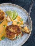 A fork with a bite of crab cake and mango-lime sauce on a great speckled plate.