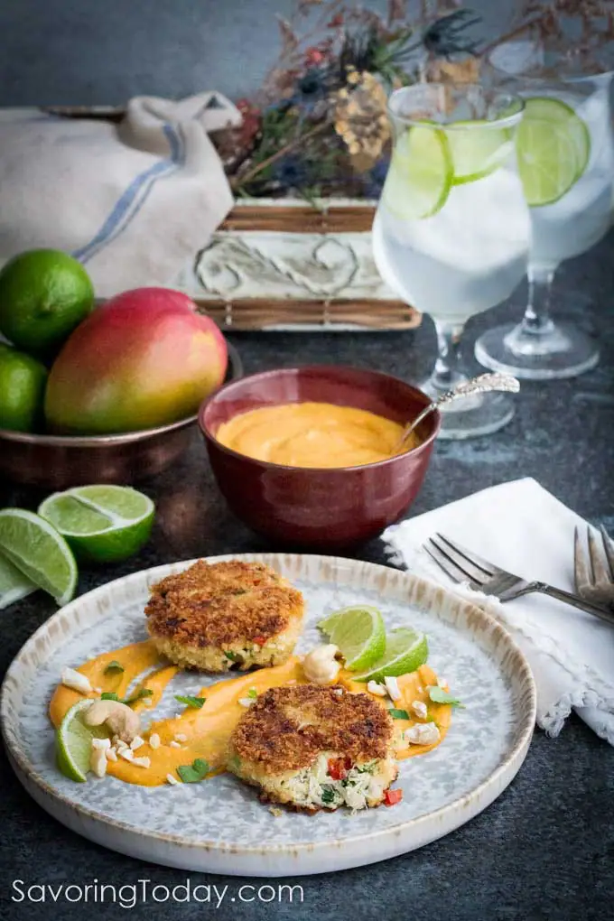Crab cakes served on a grey plate with a smear of mango lime cashew sauce.