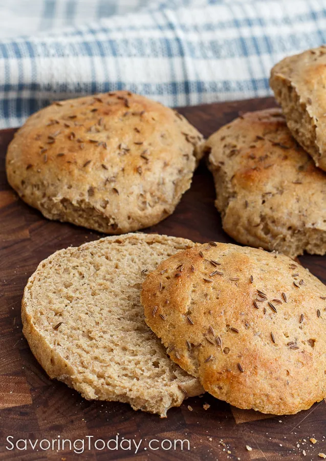 Close up of rye sandwich buns on a cutting board with one sliced open.