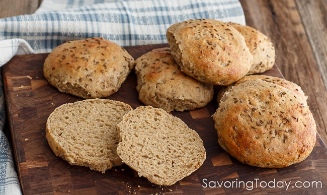 Homemade Sprouted Rye Sandwich Buns on a cutting board with a blue and white towel.