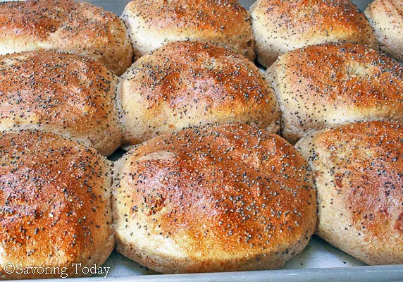 Caramelized onion burger buns with poppy seeds on a tray.