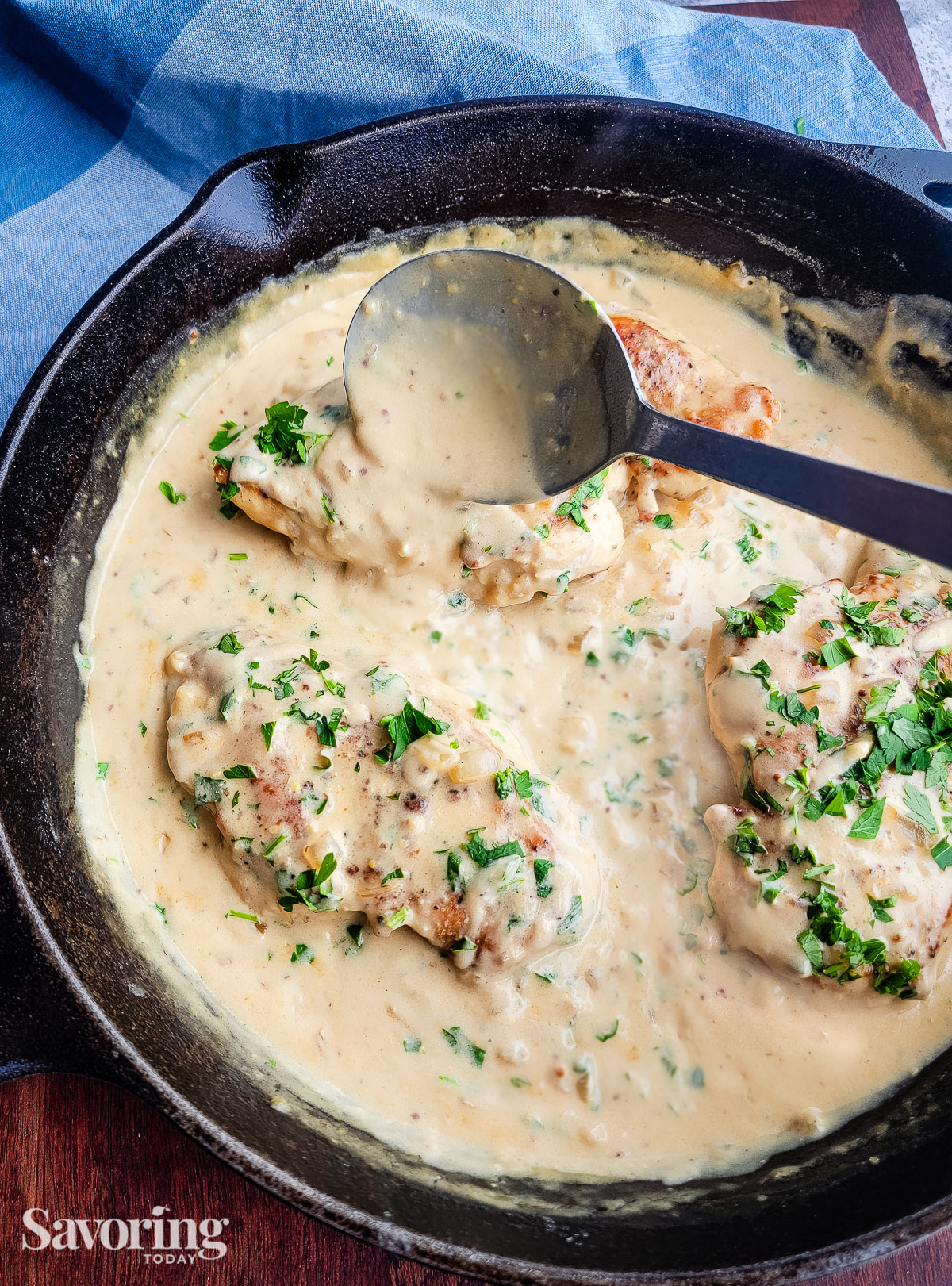 spooning sauce over chicken in cast iron skillet