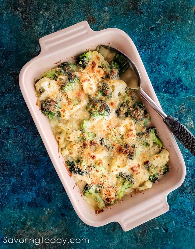 Broccoli & Cauliflower gratin casserole in a baking dish on a teal blue background.