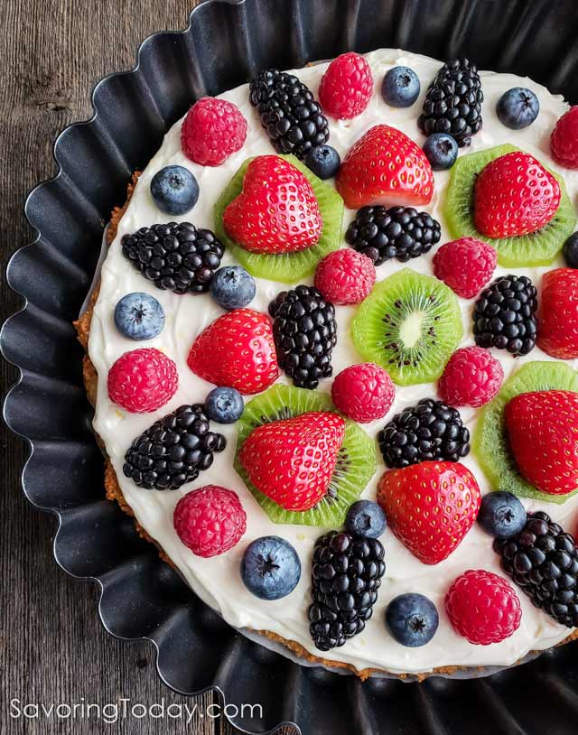Gluten-Free Cream Cheese Fruit Tart without glaze in a tart pan on a wood table.