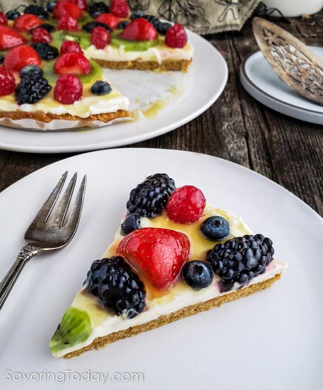 Fruit tart on a white plate on a wood table.