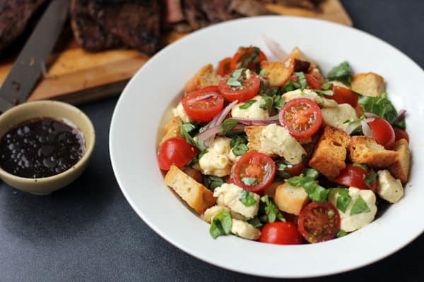 caprese-panzanella salad in a white bowl with balsamic dressing 
