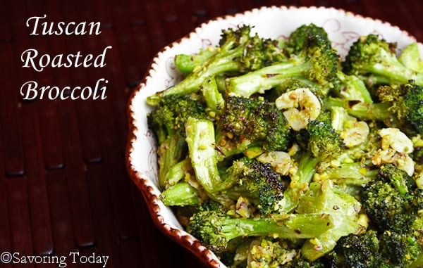 Roasted broccoli spears tossed with roasted garlic, lemon zest and Parmesan, served in a white bowl with red edges.