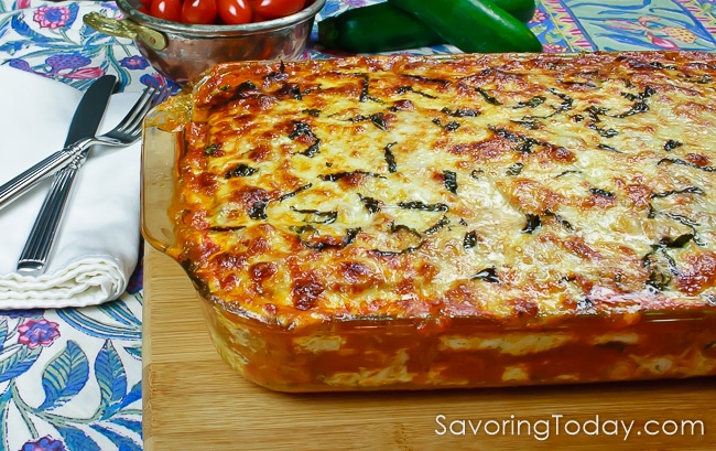 lasagna in a baking dish cooling on a cutting board