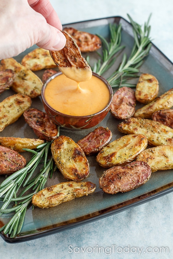 dipping a roasted potato into a gochujang sauce