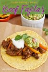 Beef fajitas with peppers, guacamole and sour cream on a corn tortilla.