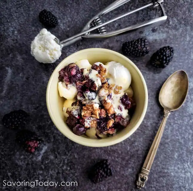 Fresh Berry crumble over vanilla ice cream in a yellow bowl.