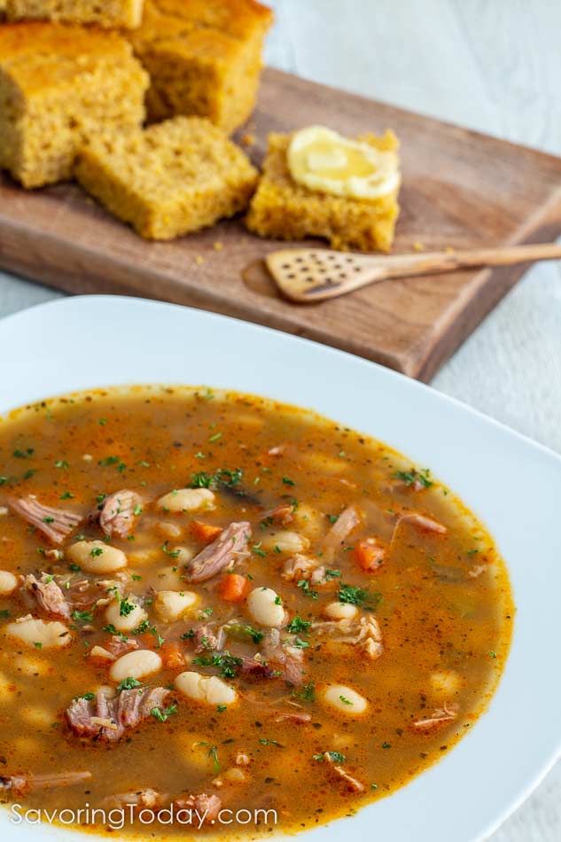 Turkey and white bean soup in a white bowl with sprouted cornbread.