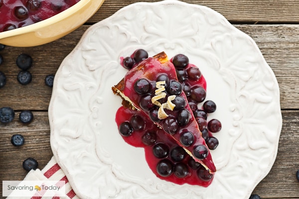 A slice of New York-Style Cheesecake. This recipe is deliciously dense and rich with a hint of lemon to balance the sweet blueberry topping.
