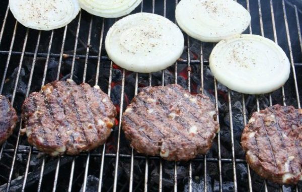 Burgers and onions on a charcoal grill.