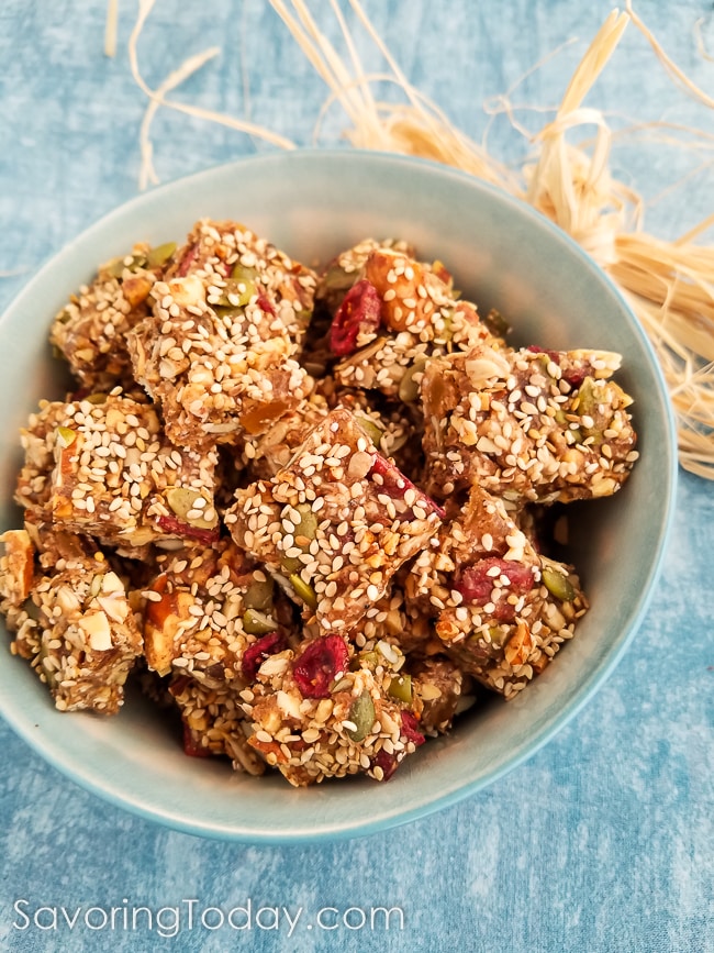 Granola square snacks with bits of ginger and cranberries in a white bowl.
