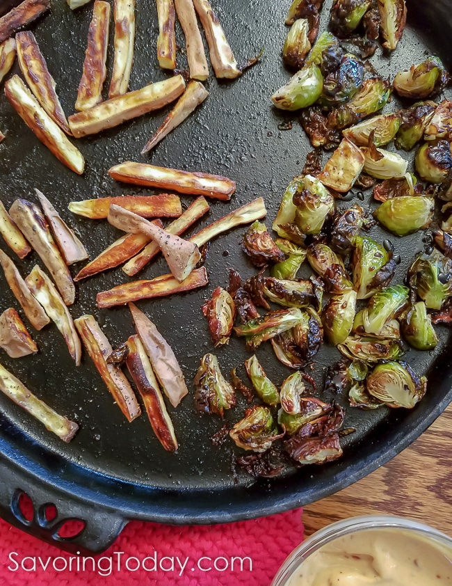 Roasted sweet potato fries and Brussels sprouts on a cast iron pizza pan. 