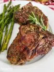 Grilled lamb chop on a white plate with asparagus