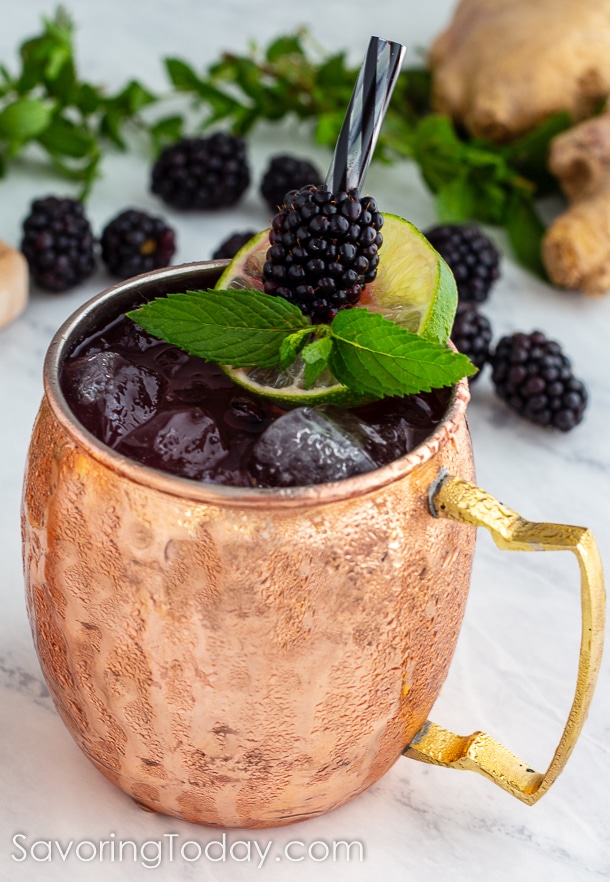 Ginger-Blackberry Cocktail in a copper mug garnished with blackberries, mint and lime. 