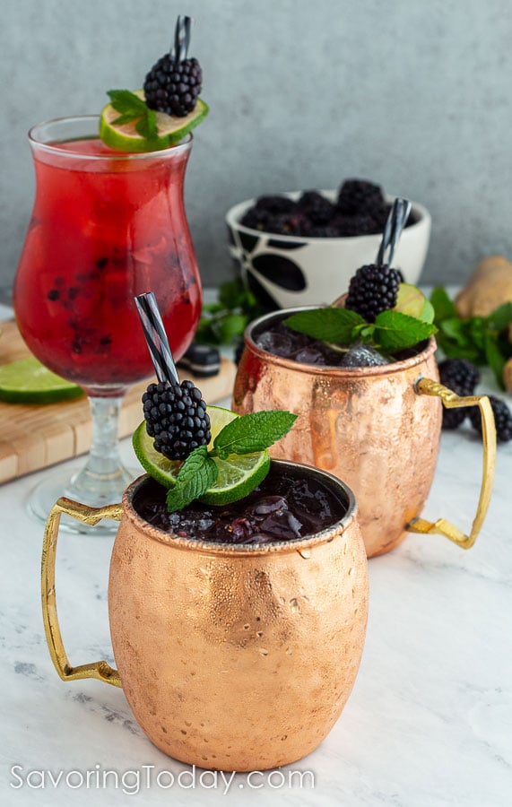 cocktails in copper mugs beside a red drink in a clear glass 