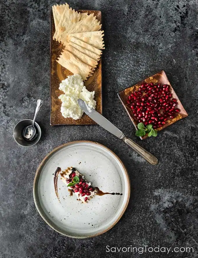 Ricotta and goat cheese spread with crackers, pomegranate seeds and balsamic vinegar.