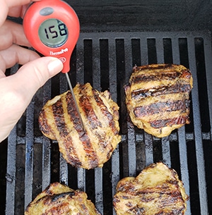 measuring the internal temp of hicken on the grill with thermomter