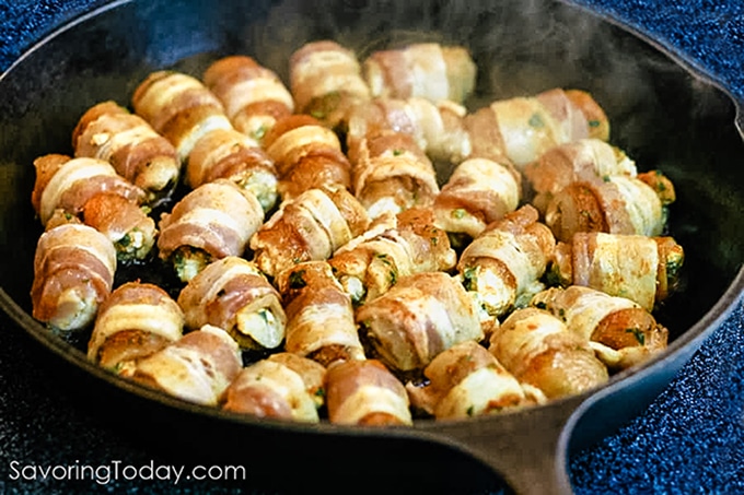 Bacon wrapped chicken jalapeno poppers frying in the skillet.