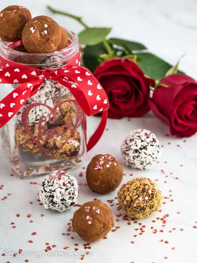 Homemade chocolate truffles in a jar with a red ribbon and white hearts for a Valentine gift.