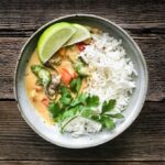 Vegetable coconut curry in a grey bowl with jasmine rice topped with lime and cilantro.