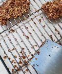 Scraping a rack to free baked on pecan crumbs.