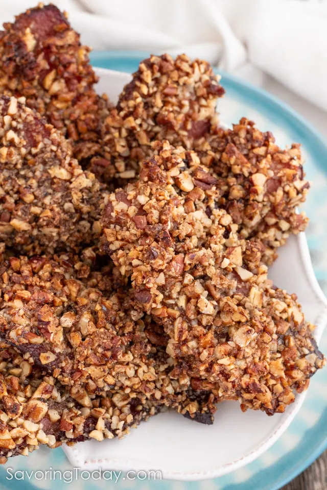 Bacon candy with a pecan crust in white dish with a blue rim.