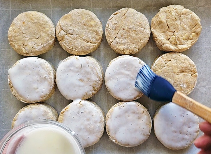 Brushing buttermilk on cut out biscuits before going in the oven.