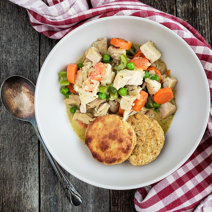 Turkey and vegetables in a cream sauce served with biscuits in a white bowl.