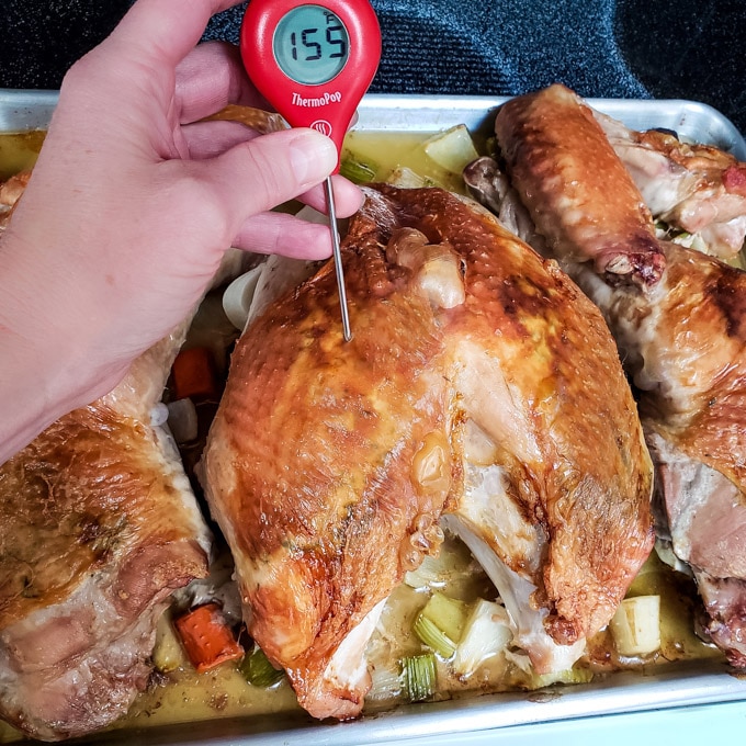 Roast turkey with a thermometer showing 155 degrees internal temperature.