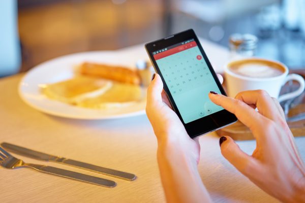 woman's hands holding a phone scheduling an appointment